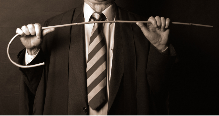 An old fashioned school master holding a cane, the type that was used for corporal punishment